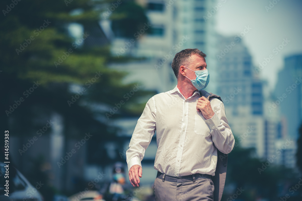 Plakat professional adult businessman wearing surgical face mask to protect of coronavirus covid-19, business worker new normal lifestyle on the background of urban city skyscraper, person in business suit