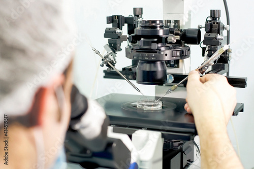 An assistant conducts medical research using the microscope in a laboratory of a Clinic of Reproductive medicine photo