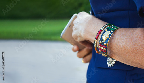 A bracelet on the arm of a mature prestigious lady of 50-60s. Close-up of a hand with a bracelet in Indian style. The concept of accessories in a fashionable image of a woman. Banner, place for text.