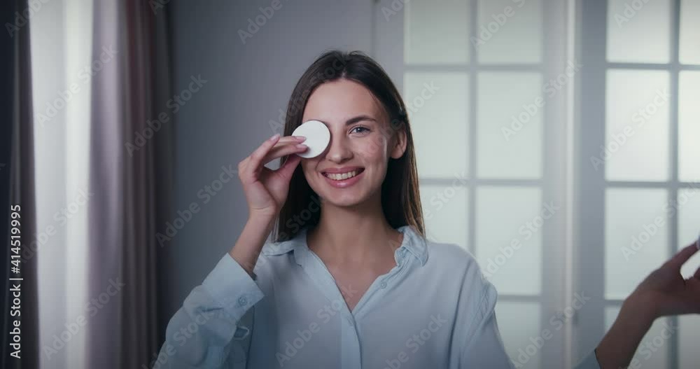Beauty portrait of happy young woman with perfect smooth skin and ideal complexion. Funny lady covering eyes with cotton pads. Body and skincare concept. Beauty portrait of happy young woman with perfect smooth skin and ideal complexion. Funny lady covering eyes with cotton pads. Body and skincare concept.