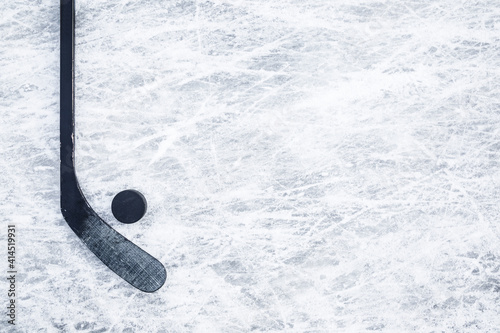 Black hockey stick and rubber puck on ice background. Closeup. Empty place for text. Top down view. photo