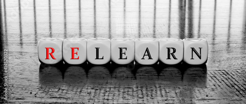 Concept of dices with letters forming word relearn or learn on a black and white background