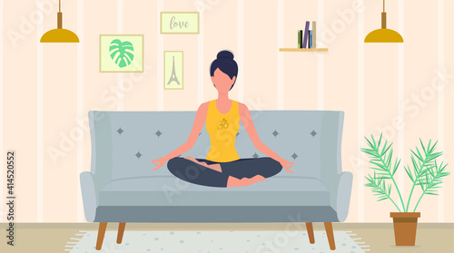 The woman is meditating sitting in the lotus pose on the sofa. Living room. 