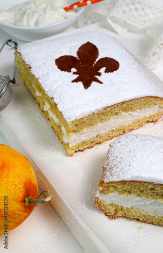 Primo piano della schiacciata fiorentina, un dolce di carnevale fiorentino al gusto di panna e arancia. Giglio fiorentino sulla torta cosparso di cacao in polvere. photo