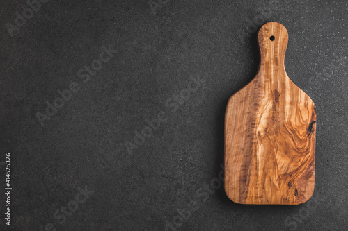 Cutting board on black textured table. View from above.	
