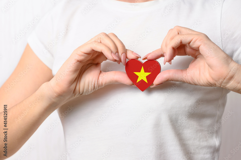 Love Vietnam. The girl holds a heart in the form of the flag of Vietnam on her chest. Vietnamese concept of patriotism Love Vietnam. The girl holds a heart in the form of the flag of Vietnam on her chest. Vietnamese concept of patriotism