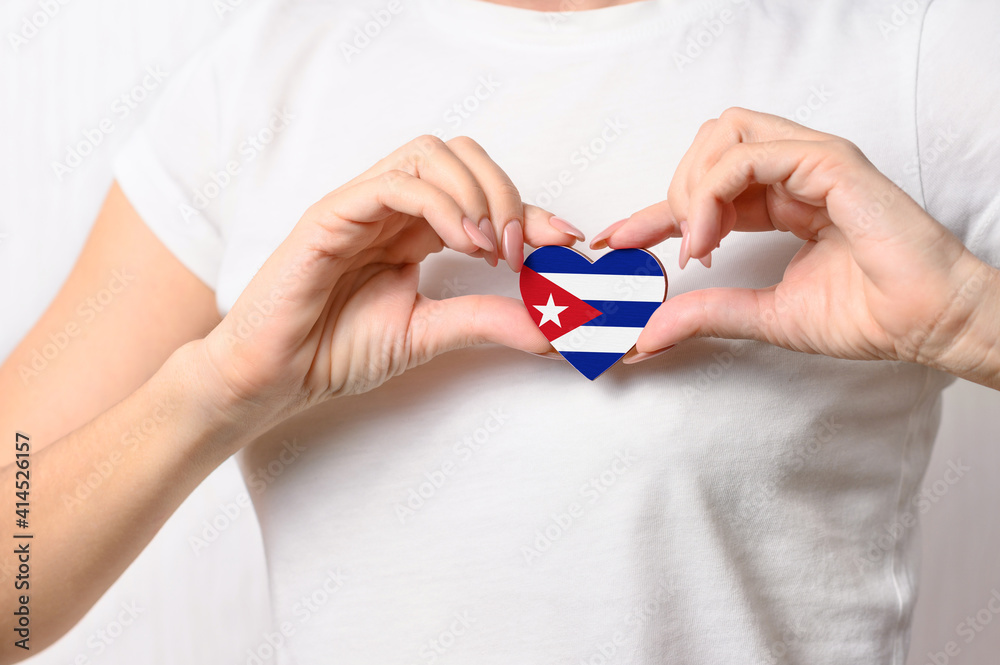 Love Cuba. The girl holds a heart in the form of the flag of Cuba on her chest. Cuban patriotism concept