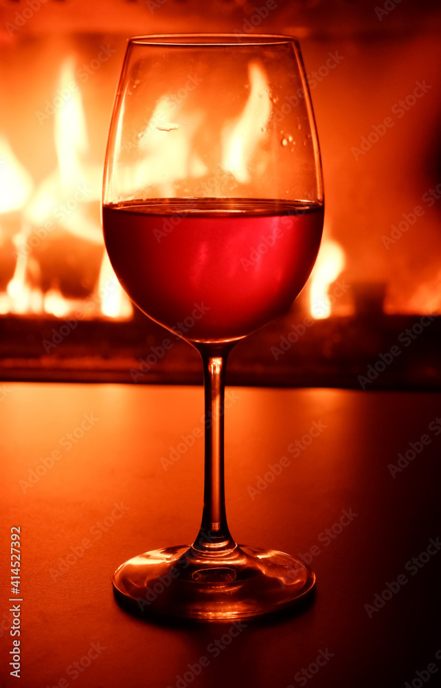Close-up of a glass of white wine in the backlight of a burning fireplace. Close-up of a glass of white wine in the backlight of a burning fireplace.