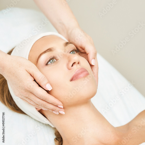 Face massage at spa salon. Doctor hands. Pretty female patient. Beauty treatment. Healthy skin procedure. Young woman head. Light background. Scrub rejuvenation. Facial dermatology mask. Detox therapy