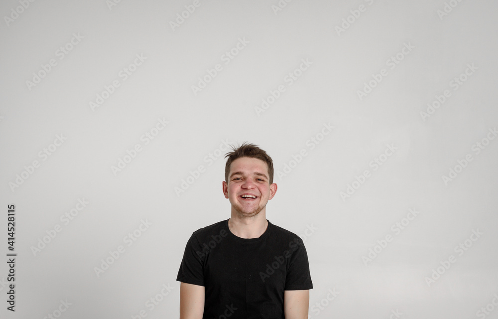 
teen guy looking at camera
 and sincerely smiling with teeth on a white background in a black T-shirt