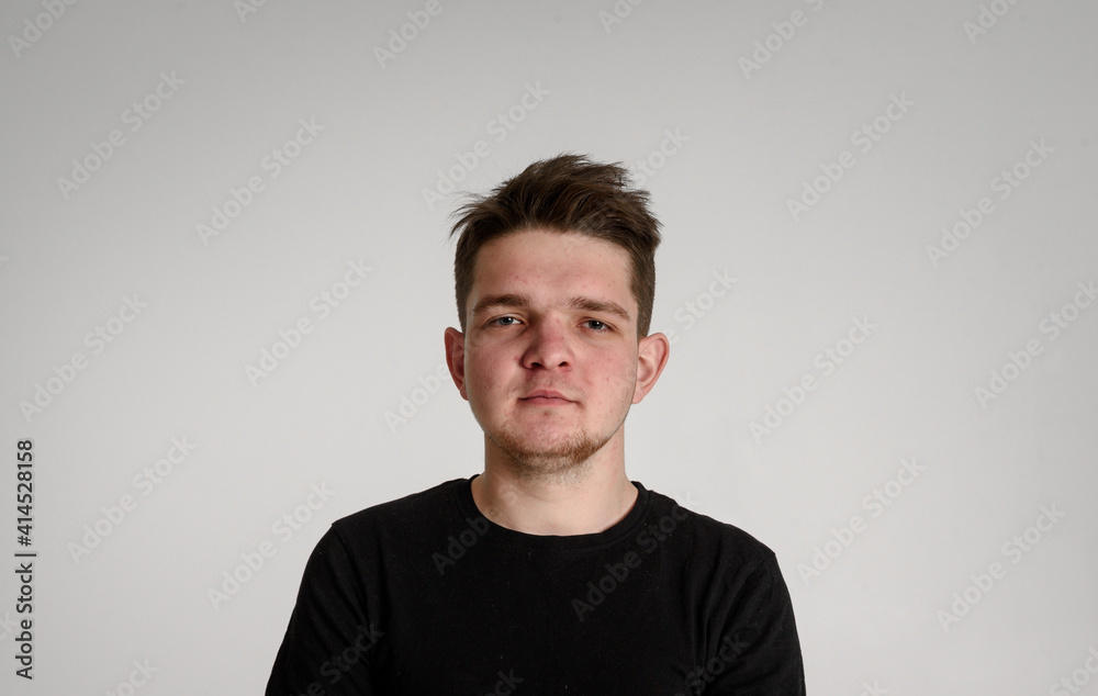 Fototapeta premium teen guy looking at camera seriously thinking about matters concerned on a white background in a black T-shirt