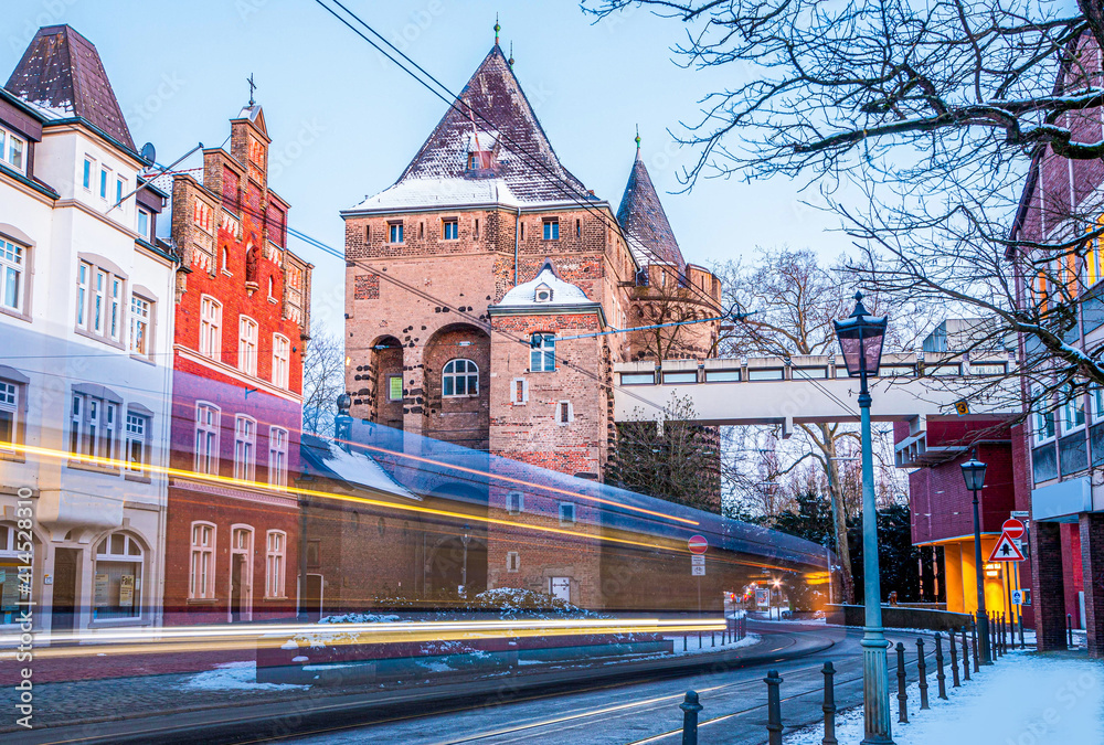 Obraz premium Lichtstreifen einer vorbeifahrenden Straßenbahn vor dem Obertor in Neuss