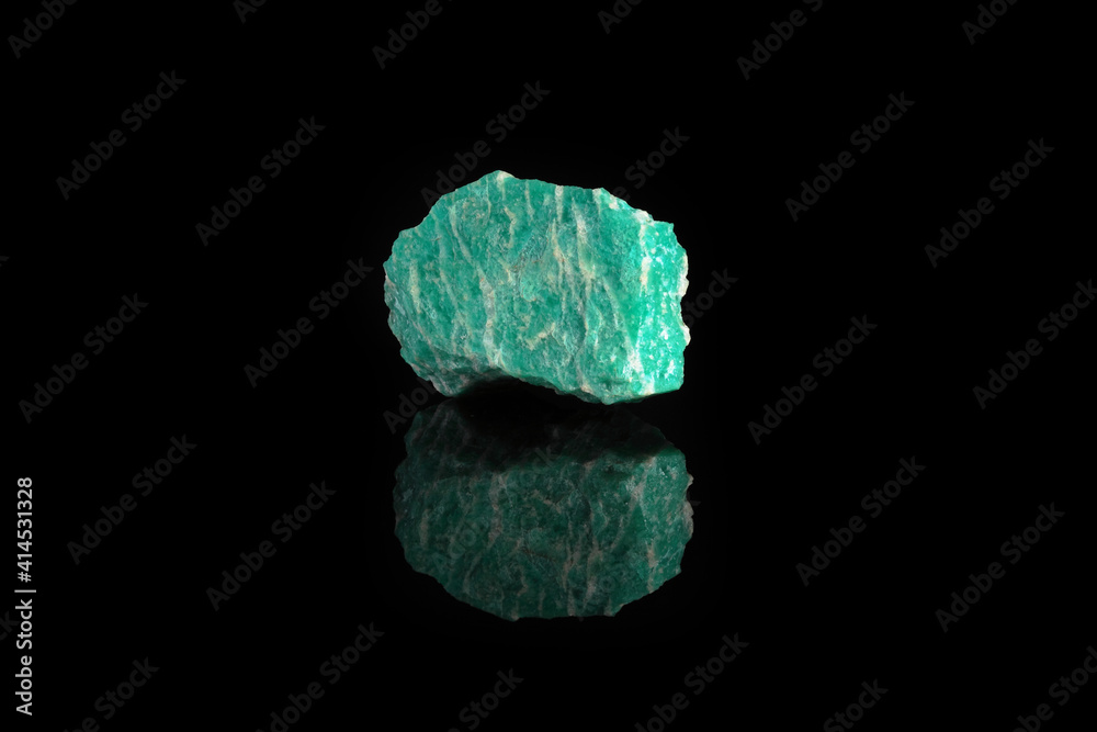 Natural rock amazonite mineral stone from Kola Peninsula on black glass background.