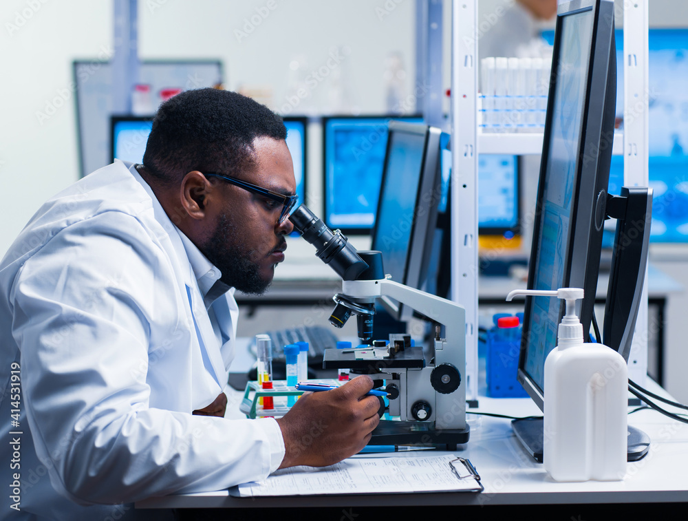Professional African-American scientist is working on a vaccine in a modern scientific research laboratory. Genetic engineer workplace. Future technology and science. Professional African-American scientist is working on a vaccine in a modern scientific research laboratory. Genetic engineer workplace. Future technology and science.