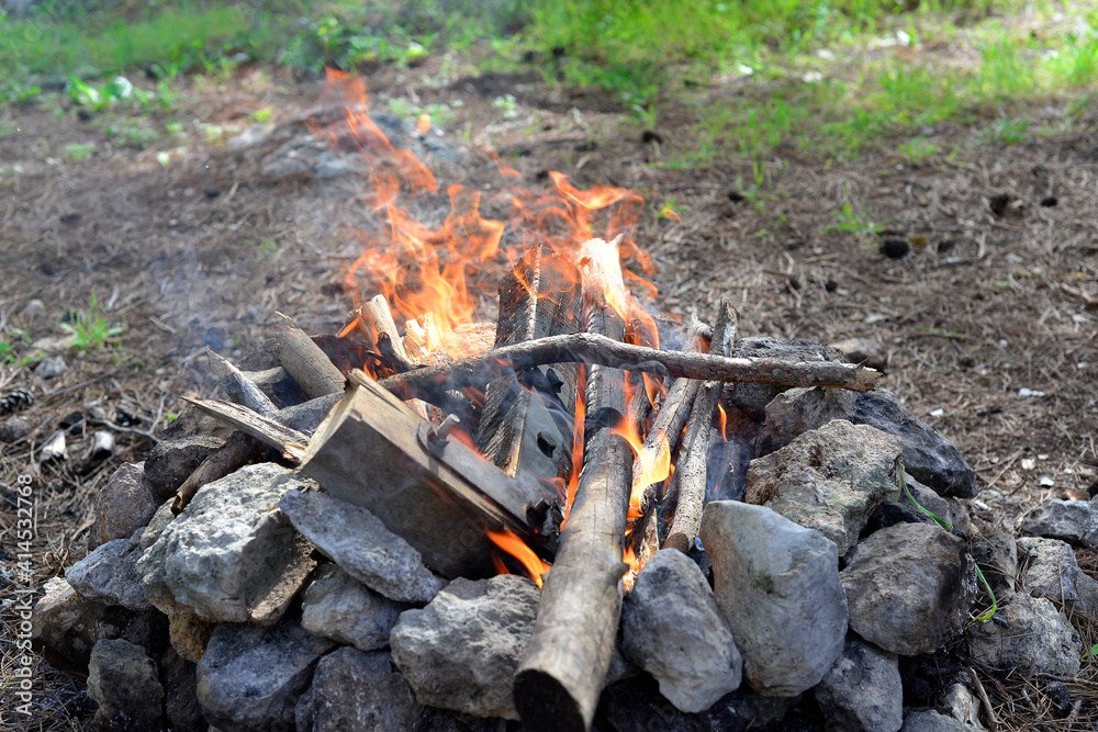 Fireplace in the forest. Smoking campfire on the nature. Camping place with wooden benches in summer forest. Campsite with campfire. Grey and brown big stones and wood for a bonfire in a fireplace Fireplace in the forest. Smoking campfire on the nature. Camping place with wooden benches in summer forest. Campsite with campfire. Grey and brown big stones and wood for a bonfire in a fireplace