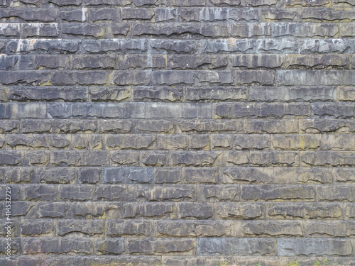 A wall with a rough textured masonry covered with divorces and darkened. Not seamless texture