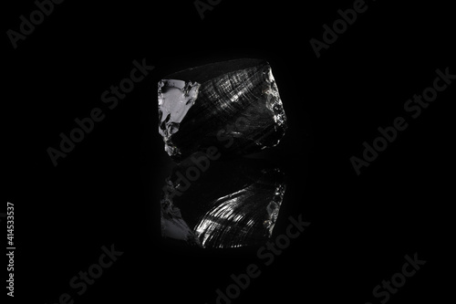 Natural rock - Obsidian, volcanic glass mineral stone from Djalaber, Armenia on black glass background. photo