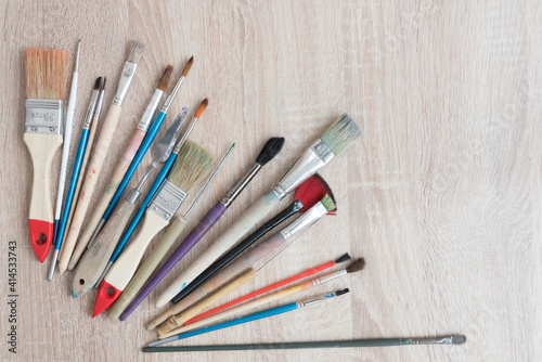 Top view of a table with a variety of artist brushes. There is room for text. Background, texture for a creative postcard