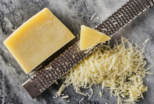 Grated parmesan cheese and grater on stone table. photo