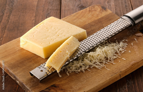 Grated cheese and grater on a wooden board