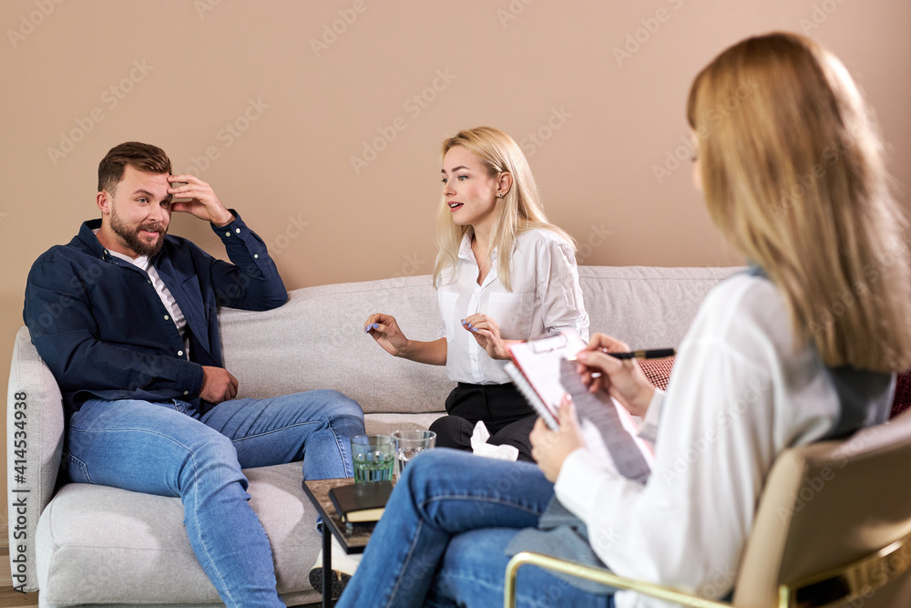 Obraz premium Gloomy woman complaining about her husband during a psychologist visit, problems and misunderstanding between two people, came to get help, need support and advice.