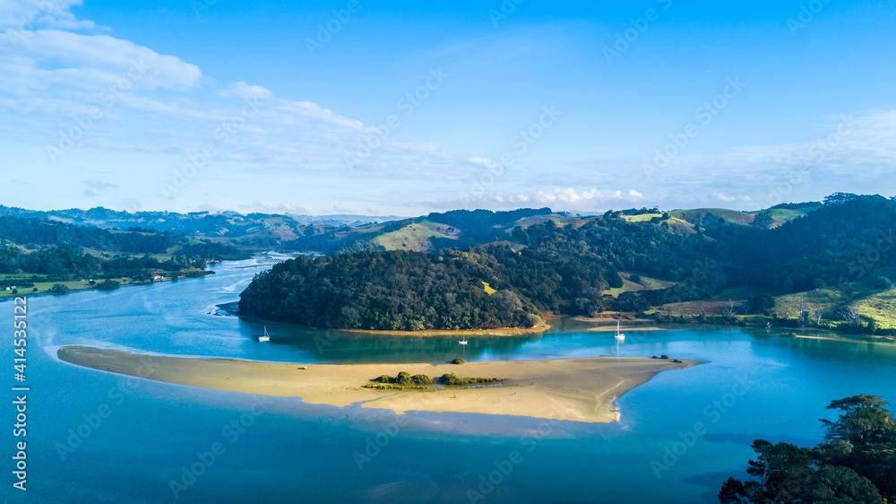 Aerial view of a beautiful river running through a green hillside to the Tasman sea. Auckland New Zealand.