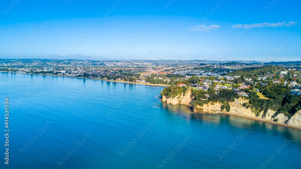 Aerial view of a beautiful suburb on the shore of a quiet harbour on a sunny morning. Auckland, New Zealand
