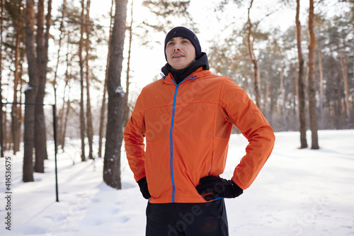 A young man in bright sports clothes enjoys a jog in the woods on a winter day