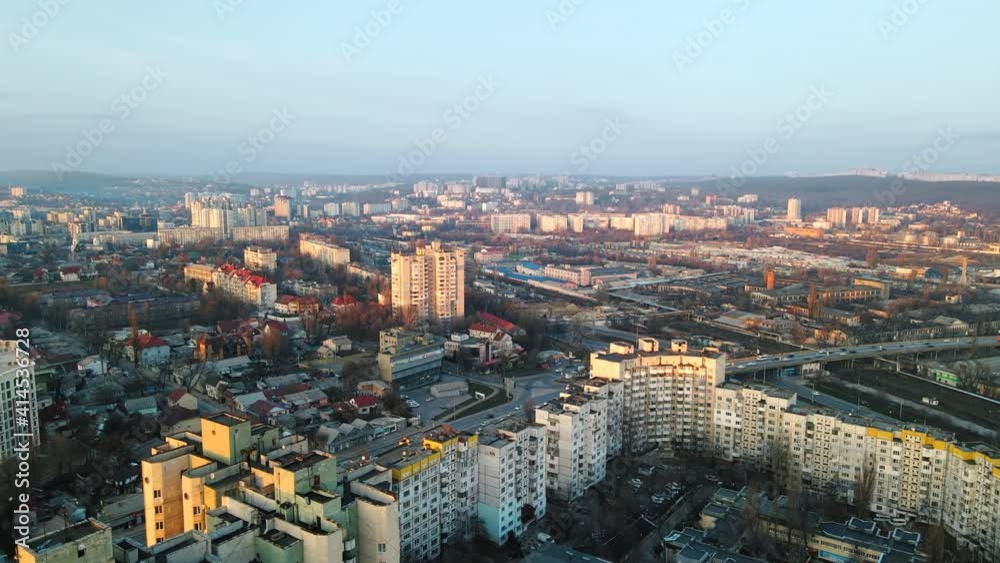 Aerial drone view of Chisinau at sunset. Multiple residential buildings, road with cars, bridge over the railroad. Bare trees, winter Aerial drone view of Chisinau at sunset. Multiple residential buildings, road with cars, bridge over the railroad. Bare trees, winter
