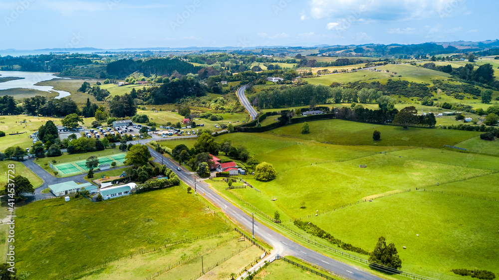 Aerial view on a highway running through countryside spotted with small farms and dwelling. Auckland, New Zealand.