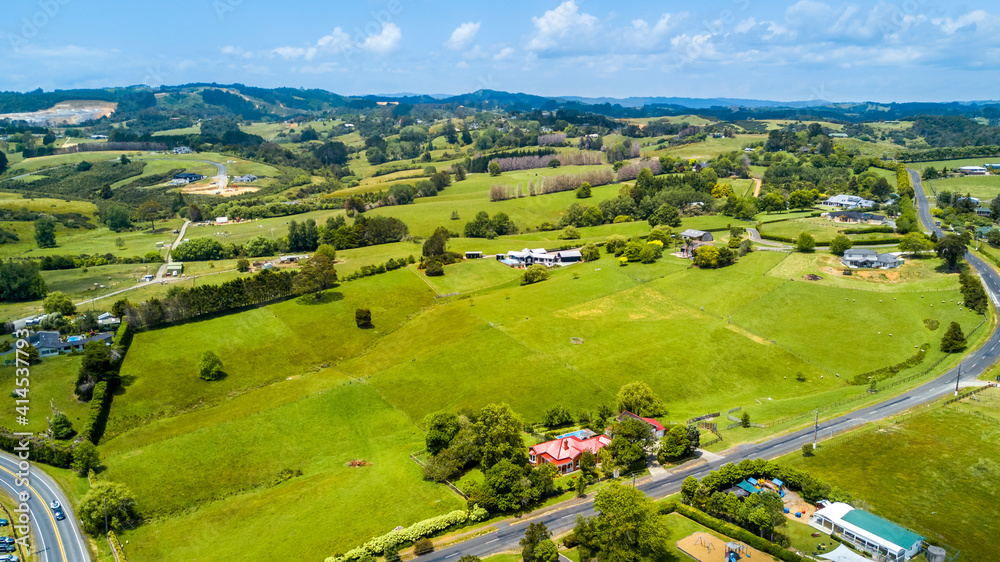 Obraz premium Aerial view on a highway running through countryside spotted with small farms and dwelling. Auckland, New Zealand.
