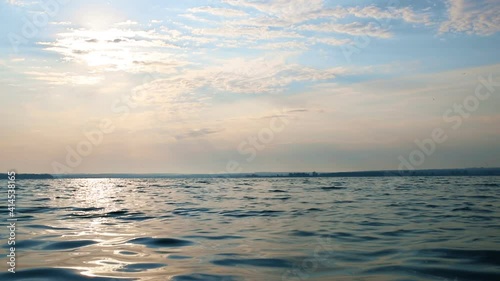 Beautiful dramatic scenic bright vibrant blue to red warm sunrise morning time landscape panorama with cloudscape reflection on ripple water surface of lake or river. Horizon coast line on background