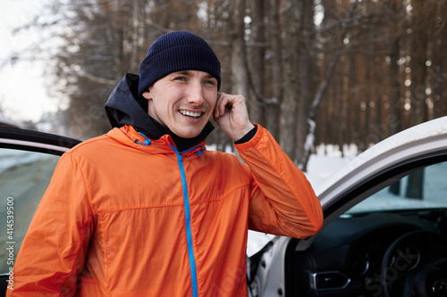 A young man turns on music in his headphones before a winter run