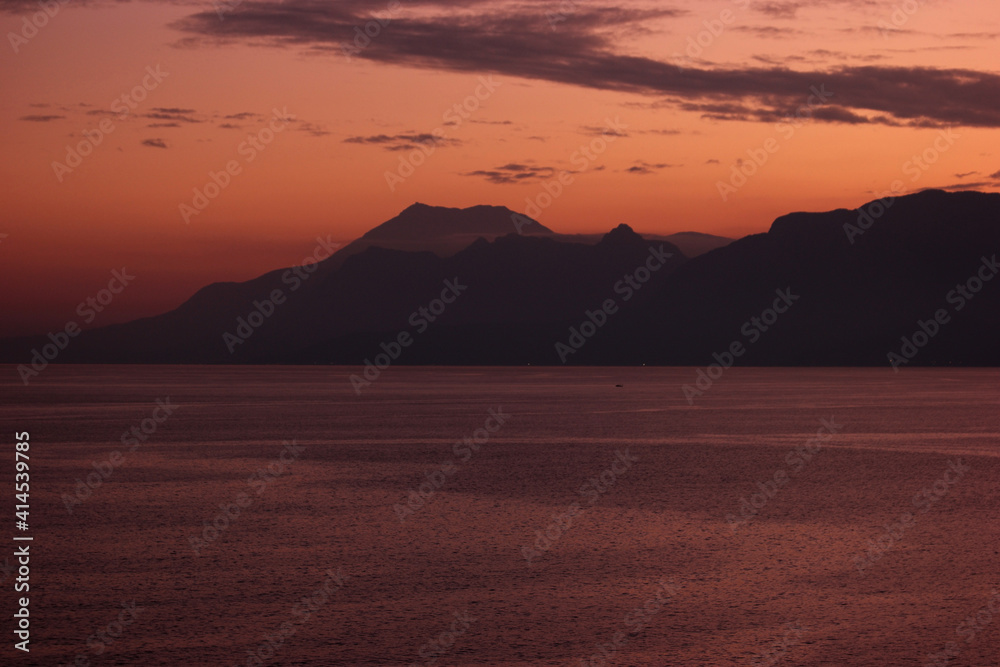 Landscape of mountains with red sunset sky background. Sunset against the background of mountains and the sea.