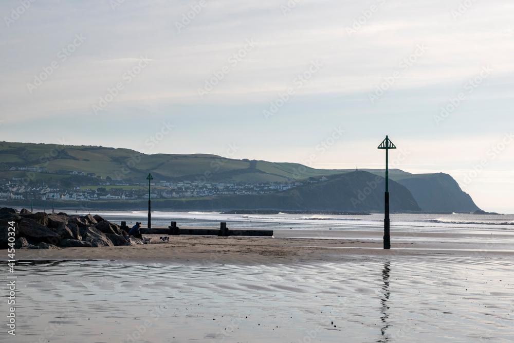 looking down Borth beach with smooth reflective sands beautiful blue sky's and groyne makers placed along the shore to warn ships and boats of danger
