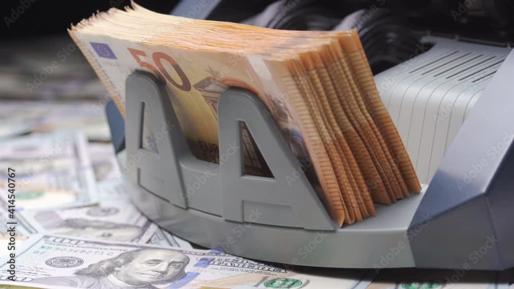 Finance concept. Macro shot of cash bill counter money machine counts 50 euro bills or banknotes. Currency counting machine stands on heap of dollars. Bank automatic equipment for calculation paper