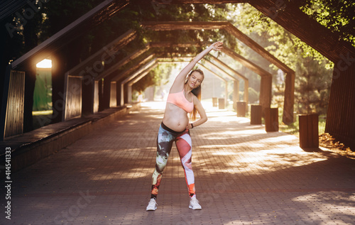 Pregnancy Fitness concept. Portrait of young pregnant woman model working outdoors. Full length