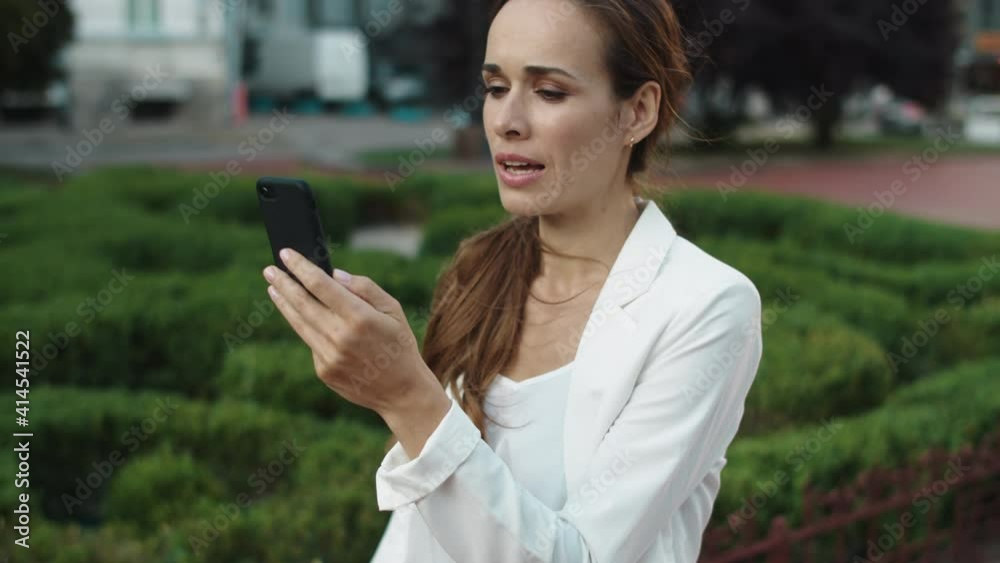 Friendly business woman speaking on video call on smartphone in city walk. Friendly business woman speaking on video call on smartphone in city walk.