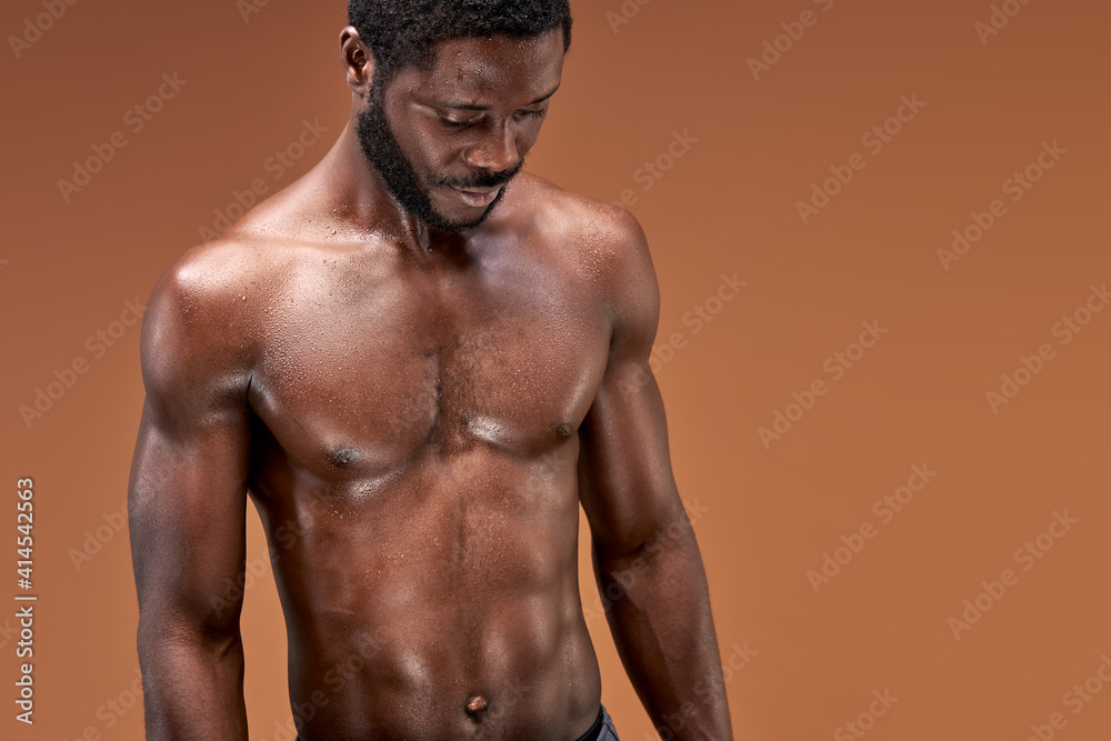 black sportsman posing at camera after active intense training, he is looking down, sweaty and exhausted black sportsman posing at camera after active intense training, he is looking down, sweaty and exhausted
