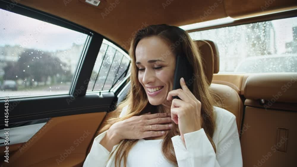 Smiling businesswoman talking on phone in back seat of luxury automobile. Smiling businesswoman talking on phone in back seat of luxury automobile.