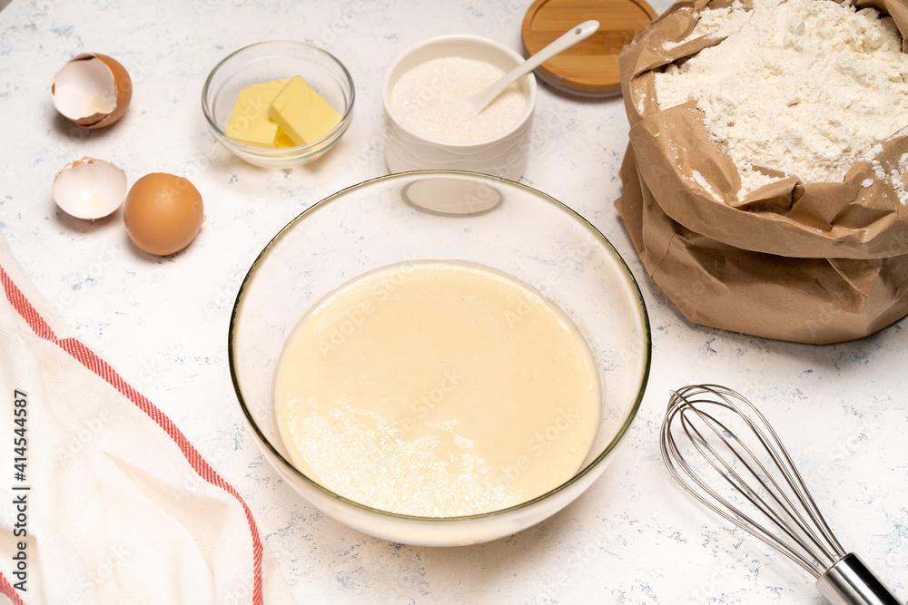 the process of making dough for pancakes with ingredients on a light table, eggs and flour are whipped with a mixer the process of making dough for pancakes with ingredients on a light table, eggs and flour are whipped with a mixer