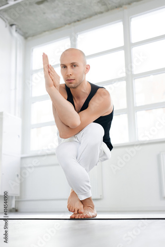 male practicing yoga,practice Eagle exercise, Garudasana pose, working out alone in yoga class, wearing sportswear, concentrated, keep balance