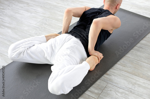 man working out, doing Frog Yin Yoga Pose, Mandukasana posture in class on fitness mat. sport, stretching, yoga concept