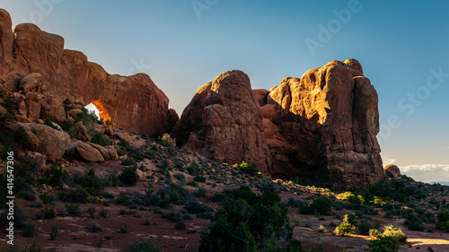 Wide shot of sunset light goes through red sandstone arch in arches national park in Utah, America