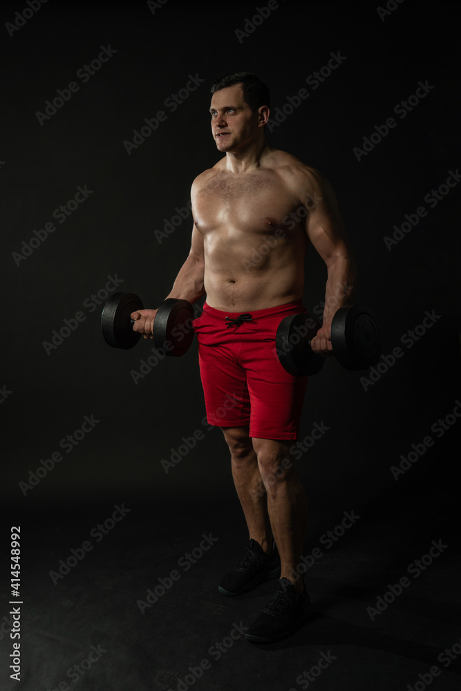 Fitness man presses dumbbells in red panties business caucasian smart, torso studio boy, success lonely background black bodybuilder