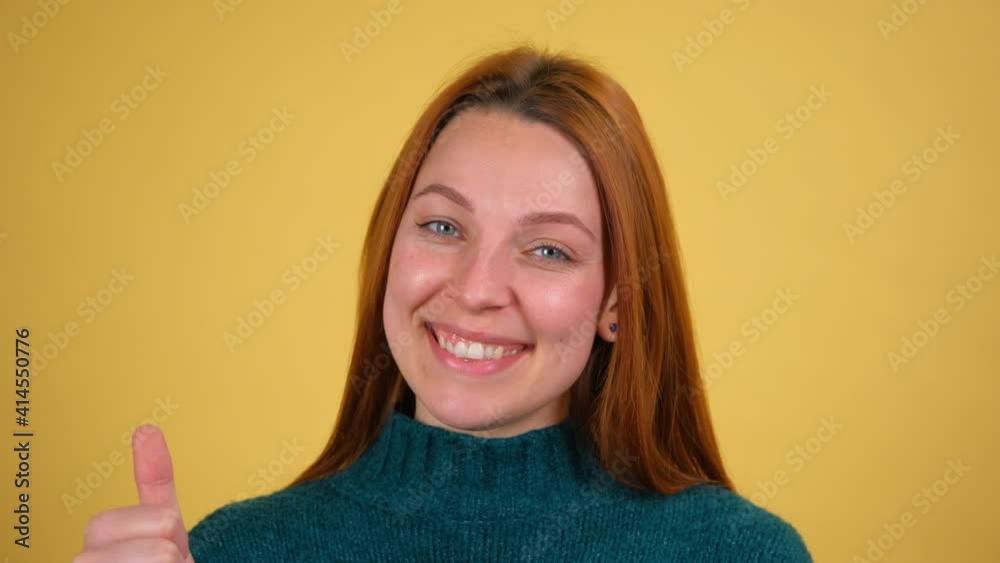 Close up young woman looking camera with charming smile blinking wink eye isolated on yellow background in studio Close up young woman looking camera with charming smile blinking wink eye isolated on yellow background in studio