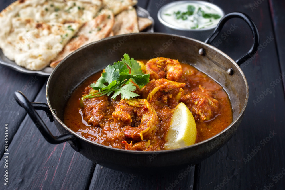Traditional Indian jhinga masala with king browns served with chapati bread and raita as close-up in a design bowl Traditional Indian jhinga masala with king browns served with chapati bread and raita as close-up in a design bowl