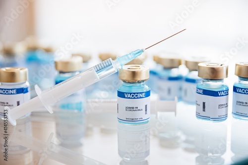 Ampoules of Covid-19 vaccine in a research lab. Syringe with a needle. Pandemic time.