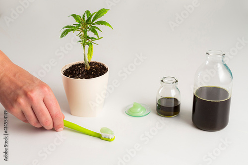 The hand takes toothbrush with CBD products around it