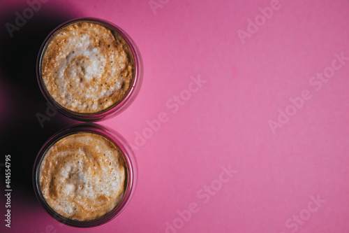 Top view of two latte art coffee in the form of figure eight, isolated on pink background.